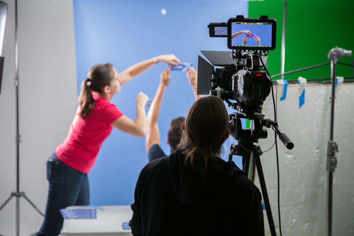 Video production crew filming on a studio set with a blue backdrop.